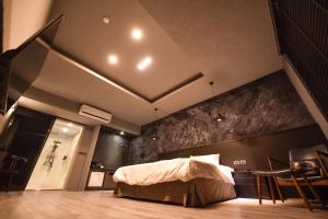 台南贰侣休闲艺术旅馆的卧室配有一张床铺,位于带椅子的房间