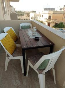 Siġġiewi"Joseph 2" Stylish corner flat with open views, just 5km from the beach的阳台上的木桌和椅子