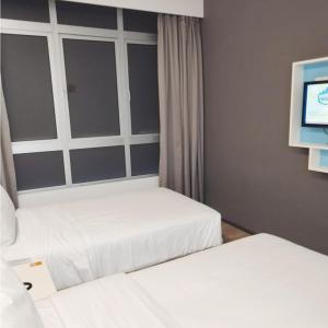 云顶高原Room in Genting Highland的一间卧室设有两张床,墙上配有电视。