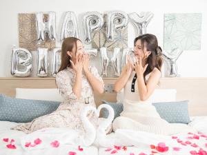 名古屋Vessel Inn Sakae Ekimae的两名女士坐在床上,戴着香槟杯
