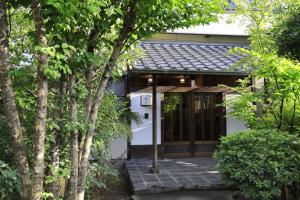 Isawa貸切温泉風呂付 ゲストハウス璃洛-りらく- 石和温泉 日本式宿 健康朝食付的树木房屋的入口