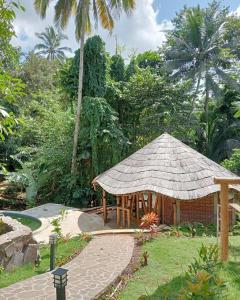 外南梦The Osing Bamboo Resort - a LIBERTA Collection的花园中带草屋顶的凉亭