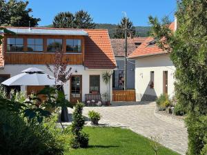 DunabogdányKis-Duna Vendégház的白色的房子,带雨伞和庭院