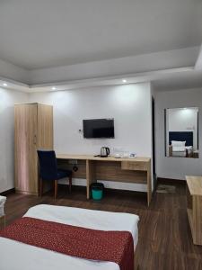 甘托克Shanol Residency的酒店客房设有一张床、一张书桌和一台电视机。