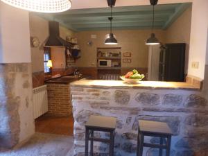 OrgazCasa Cuqui的厨房配有石制柜台和2张凳子