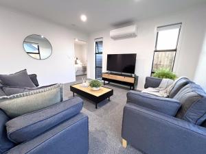 汉密尔顿Villa in Central Hamilton - By KOSH BNB的客厅配有2张蓝色沙发和1台电视