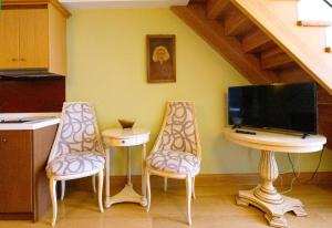 罗希姆诺Civitas Suites Hotel的厨房配有两把椅子、一台电视和一张桌子