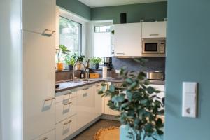 默讷塞Familiensuite BoHo am See - Netflix - Grill - Parken的厨房配有白色橱柜和盆栽植物