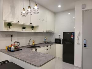新山Sky Trees at AEON Bukit Indah with Netflix and Wifi的厨房配有白色橱柜和黑色冰箱。