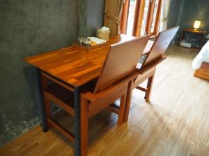 大城Banmai87 Guest House บ้านไม้87 เกสต์เฮ้าส์的一张带两把椅子的木桌和一张书桌