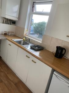 阿什顿下安林恩New 2 bedroom Apartment in Greater Manchester的厨房配有白色橱柜、水槽和窗户。