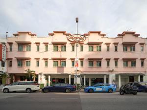 新加坡Amrise Hotel, Check in at 10PM, Check out at 9AM的一座大型粉红色建筑,前面有汽车停放