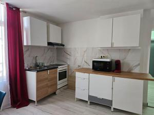 蒙斯Grand Appartement cosy et lumineux的厨房配有白色橱柜和红色窗帘