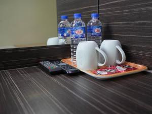 新加坡Amrise Hotel, Check in at 10PM, Check out at 9AM的托盘,装有两杯和两瓶水