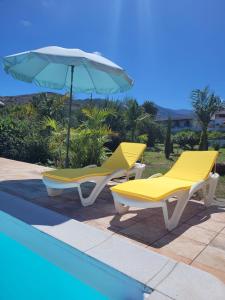 圣布里希达Casa con piscina, High-speed Wi-Fi y vistas的游泳池旁的两把黄色椅子和一把遮阳伞
