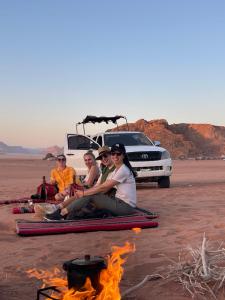 瓦迪拉姆Wadi Rum Star Camp的一群人坐在沙漠的火堆旁