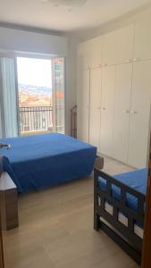 瓦拉泽Vista mare con ogni comfort的一间卧室设有蓝色的床和大窗户