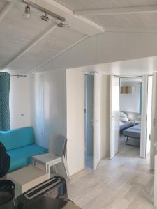 旺代蒙塔利韦Mobil Home Comfort XL 6 Personnes Montalivet的一间带蓝色沙发的客厅和一间卧室
