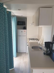 旺代蒙塔利韦Mobil Home Comfort XL 6 Personnes Montalivet的一间带水槽和炉灶的小厨房