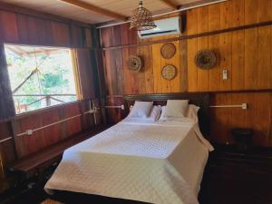 马瑙斯Ponta Poranga Jungle Lodge的木制客房内的一间卧室,配有一张床
