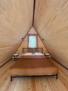 安布罗劳里Agaruka Cabin Racha的木制客房的一张床位,设有窗户