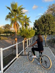 瓦尔杜德弗拉德斯Quinta do Pinheiro Hotel Rural - GQL的一名妇女在围栏附近骑着自行车