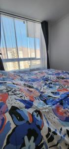 伊基克Departamento Lynch Iquique的床上的五颜六色的被子和窗户