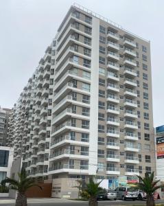 利马Tú hogar frente al mar的一座大型公寓楼,前面有棕榈树