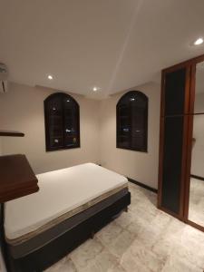 曼加拉蒂巴Casa em mangaratiba的一间卧室设有一张大床和两个窗户