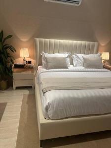 利雅德Three Bedroom furnished apartment in north Riyadh的白色的床、白色枕头和带台灯的桌子