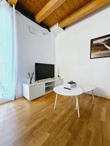 帕多瓦Giotto Apartment的白色的客厅配有桌子和电视。