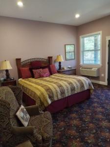 KamiahHearthstone Elegant Lodge的卧室配有床、椅子和窗户。