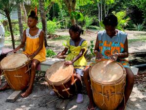 霍普金斯Palmento Grove Garifuna Eco-Cultural & Healing Institute的三个小孩在板凳上玩鼓