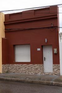 米纳斯Casa amueblada en centro de Minas, Lavalleja的红色的建筑,有白色的门和窗户