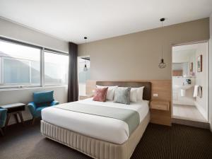 墨尔本Saint Kilda Beach Hotel - formerly Rydges St Kilda的酒店客房,配有一张床和一张蓝色椅子