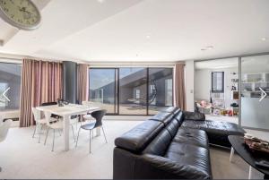 奥克兰Apartment with Brilliant views in Auckland CBD的客厅配有黑色真皮沙发和桌子