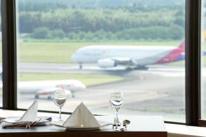 成田成田马罗德国际酒店的一张桌子,上面放着两杯酒,还有一个飞机在跑道上