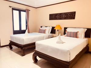 清迈Na Thapae Chiangmai Hotel的一间卧室设有两张床和窗户。