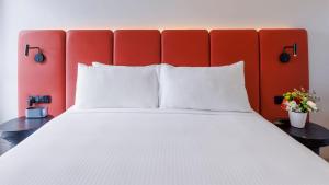 波高尔宾Elysia Wellness Retreat的一张带白色枕头和红色床头板的床