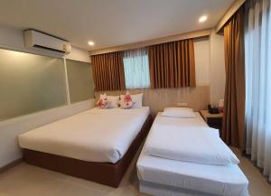 清迈Malee Hotel的一间卧室设有两张床和窗户。