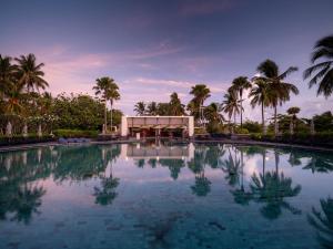 卡伦海滩Pullman Phuket Karon Beach Resort的一座楼前种有棕榈树的游泳池