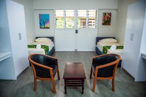 苏瓦Yatulau Hotel and Conference的一间客房配有两张床、一张桌子和两把椅子