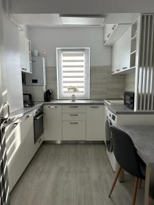 苏恰瓦Luxury Apartments and Studios Boulevard G Enescu Suceava的厨房配有白色橱柜、桌子和窗户。