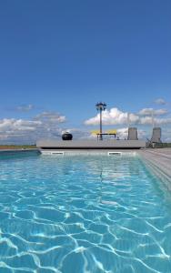 Villers-la-VilleB&B Les Autres Sens的蓝色海水游泳池、桌子和椅子