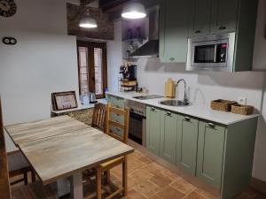 马德里加尔德拉韦拉Casa Rural: La casa El cura的厨房配有绿色橱柜和木桌