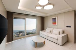 釜山NewCZ Osiria Residence的带沙发、桌子和窗户的客厅