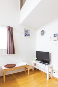 福冈博多駅東貸切Hakataekihigashi Apartment LOFT付き高速WIFI 敷地内駐車場 地下鉄5分 国際線博多駅徒歩圏内的白色的客厅配有长凳和电视。