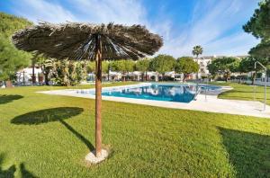 奇克拉纳－德拉弗龙特拉Carrajolilla Sancti petri的游泳池旁草地上的遮阳伞