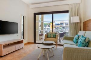 阿德耶皇家日落海滩俱乐部钻石度假公寓的客厅配有电视、沙发和桌子