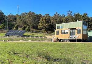 AlonnahLittle Pardalote Tiny Home Bruny Island的一座带太阳能电池板和田野的小房子